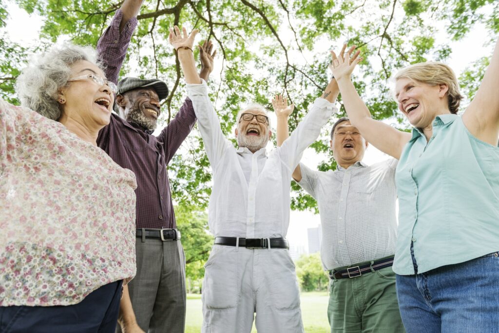 Group of happy retired senior friends in the park cheering